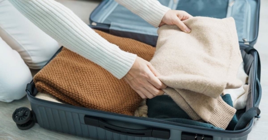 Woman packing her winter clothes in luggage